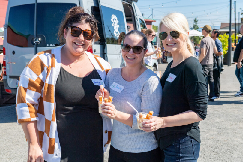 Three women stand together, smiling at a Morrison appreciation event.