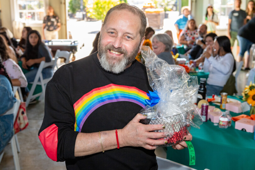 A man holds a gift basket smiling at Morrison appreciation event.