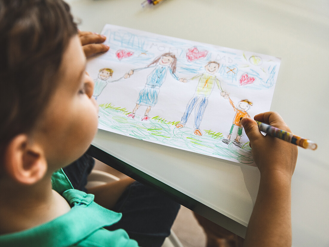 Child drawing picture of happy family.