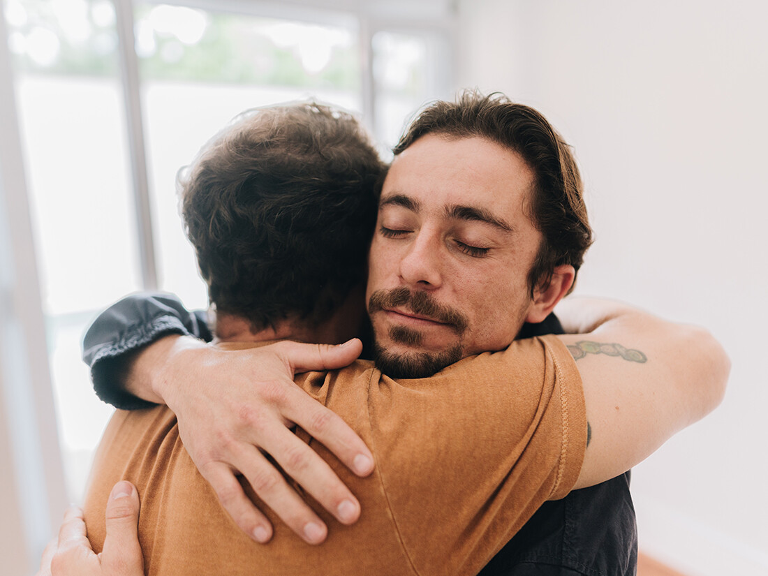 Two people hugging, focus on man's content face